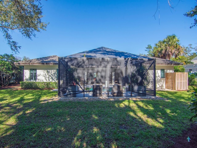 rear view of house featuring a lawn, glass enclosure, and a pool