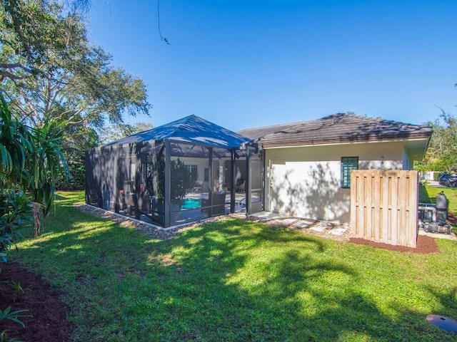 rear view of property featuring a lawn and glass enclosure