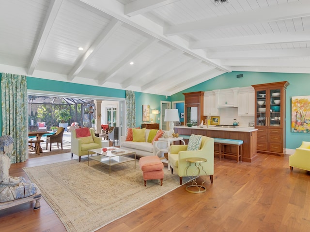 living room featuring vaulted ceiling with beams and light wood-type flooring