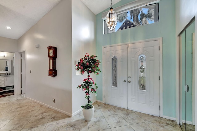 tiled foyer with a high ceiling, an inviting chandelier, and sink