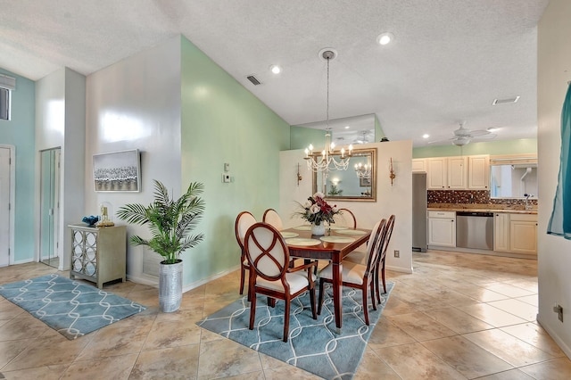 dining space featuring sink, a textured ceiling, light tile patterned floors, ceiling fan with notable chandelier, and high vaulted ceiling