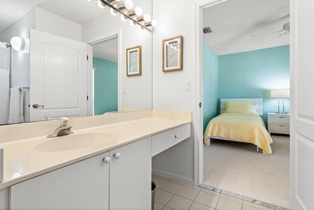 bathroom with ceiling fan, a textured ceiling, tile patterned floors, and vanity