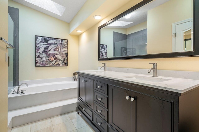 bathroom with vanity, tile patterned flooring, a bathing tub, a skylight, and a textured ceiling