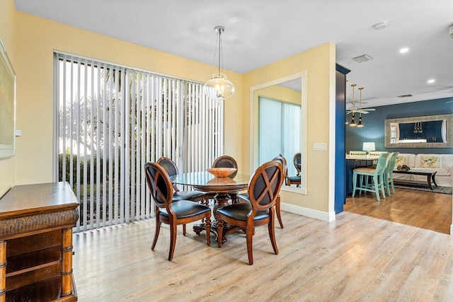 dining room with ceiling fan with notable chandelier and light wood-type flooring