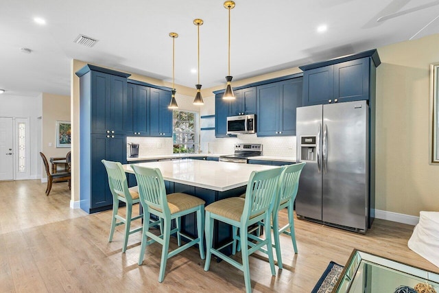 kitchen featuring decorative light fixtures, light hardwood / wood-style floors, a center island, blue cabinetry, and stainless steel appliances