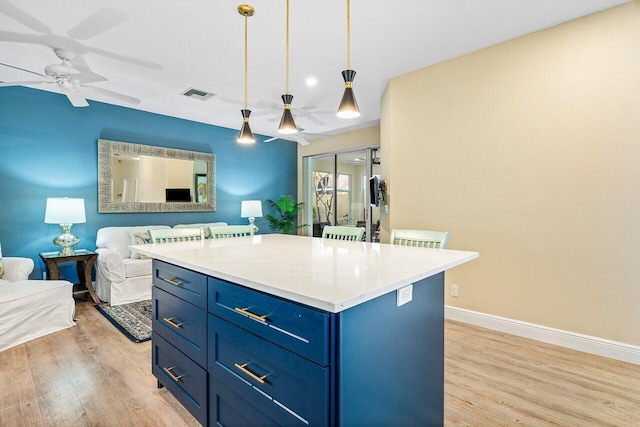 kitchen featuring ceiling fan, a center island, hanging light fixtures, light wood-type flooring, and blue cabinets