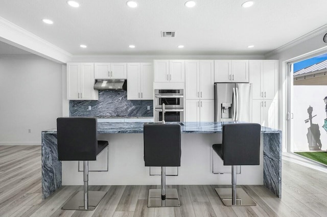 kitchen featuring white cabinets, a kitchen breakfast bar, and appliances with stainless steel finishes