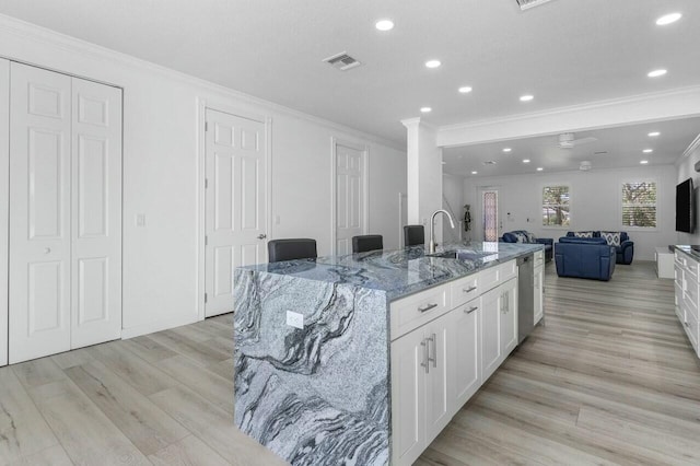 kitchen featuring sink, white cabinetry, dishwasher, stone counters, and a center island with sink