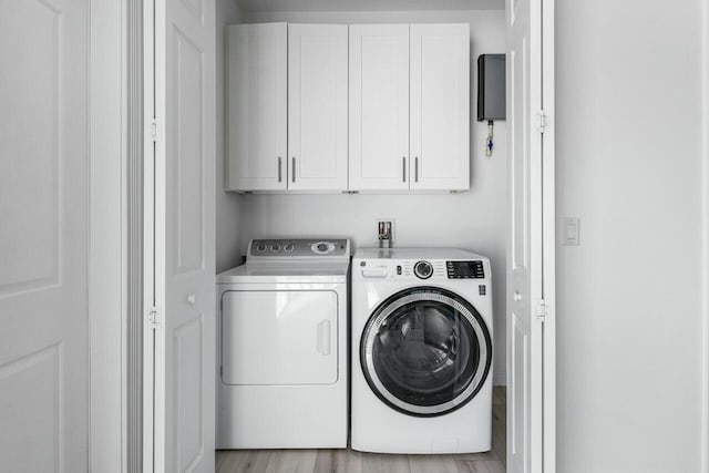 clothes washing area featuring independent washer and dryer, cabinets, and light hardwood / wood-style flooring