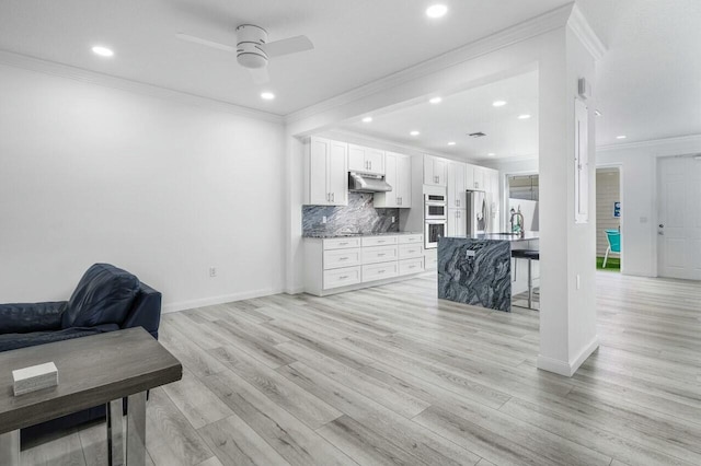 kitchen featuring stainless steel appliances, crown molding, ceiling fan, white cabinets, and tasteful backsplash