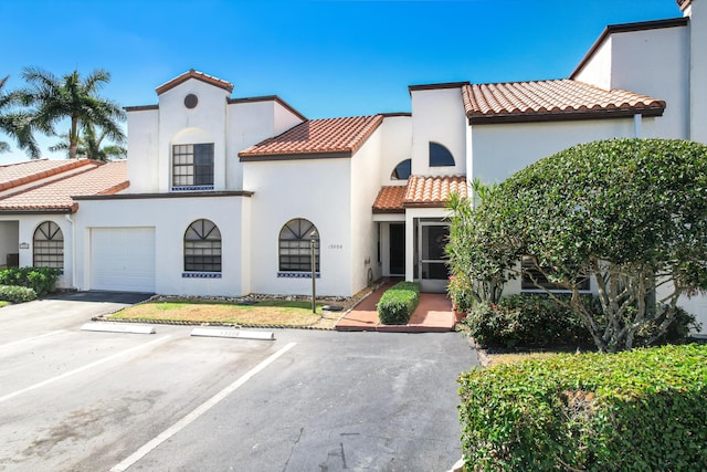 mediterranean / spanish house featuring uncovered parking, a tile roof, and stucco siding