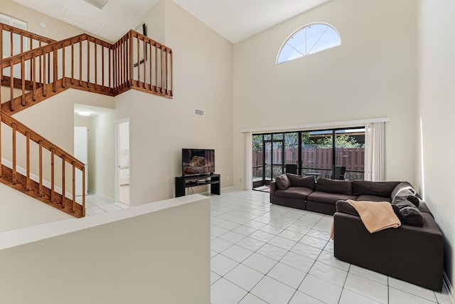 living room with light tile patterned floors, baseboards, visible vents, stairway, and a high ceiling