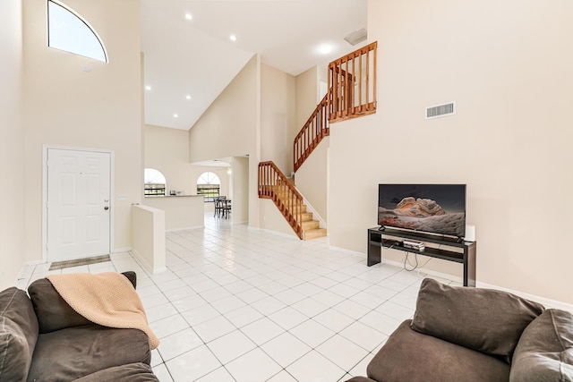 living area featuring light tile patterned floors, baseboards, visible vents, stairway, and a high ceiling