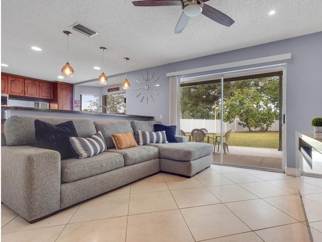 living room with ceiling fan, light tile patterned floors, and a textured ceiling