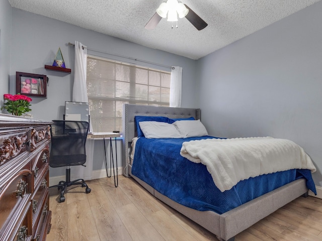 bedroom with ceiling fan, a textured ceiling, and light wood-type flooring