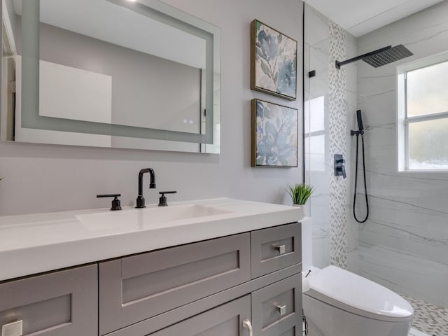 bathroom featuring tiled shower, vanity, and toilet