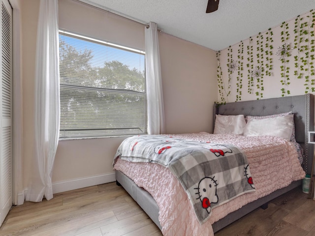 bedroom with ceiling fan, a closet, a textured ceiling, and light wood-type flooring