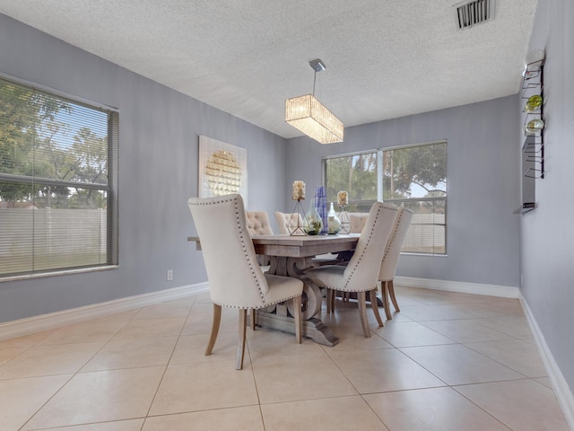 tiled dining space featuring a textured ceiling, an inviting chandelier, and plenty of natural light