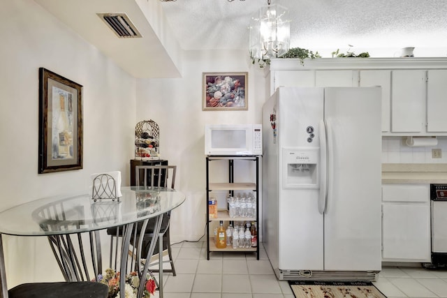 1102 Greenpine Blvd Unit A1, West Palm Beach, FL 33409 - kitchen featuring white appliances, light tile patterned floors, light countertops, white cabinetry, and a textured ceiling
