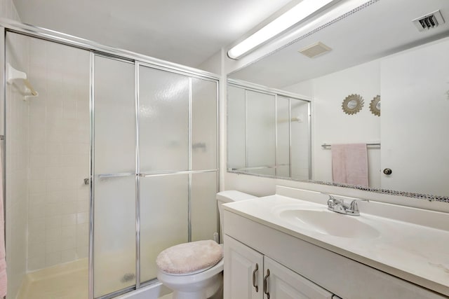 bathroom with a shower with door, vanity, and toilet