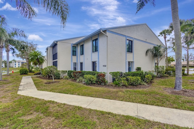 1102 Greenpine Blvd Unit A1, West Palm Beach, FL 33409 - view of home's exterior featuring stucco siding and a lawn
