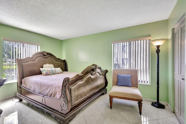 bedroom with light tile patterned floors, a textured ceiling, and a closet