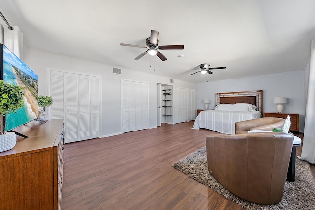 bedroom with hardwood / wood-style flooring, ceiling fan, and two closets