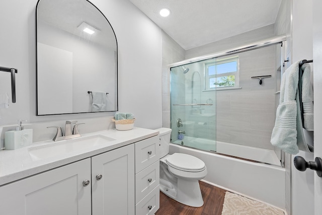 full bathroom featuring vanity, hardwood / wood-style floors, toilet, and combined bath / shower with glass door