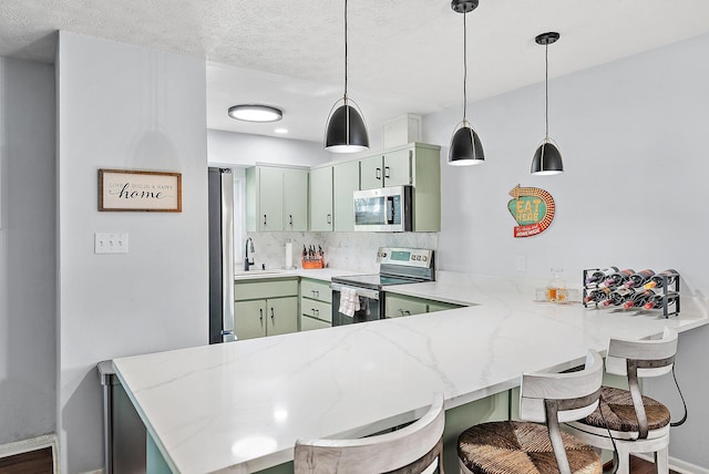 kitchen with stainless steel appliances, sink, kitchen peninsula, and green cabinetry