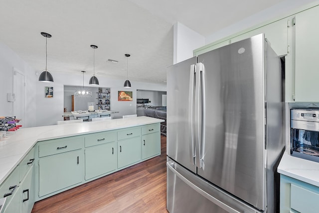 kitchen with stainless steel refrigerator, dark hardwood / wood-style flooring, a chandelier, hanging light fixtures, and light stone countertops