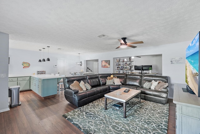 living room featuring ceiling fan, dark hardwood / wood-style floors, and a textured ceiling