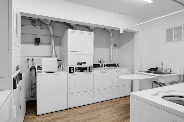 clothes washing area with sink, stacked washer and dryer, light wood-type flooring, and independent washer and dryer