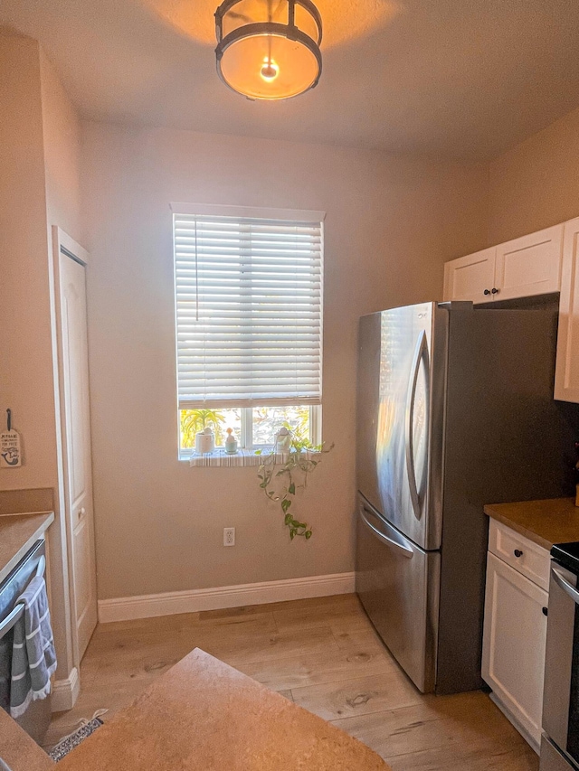 kitchen featuring range, stainless steel fridge, white cabinetry, and light hardwood / wood-style flooring