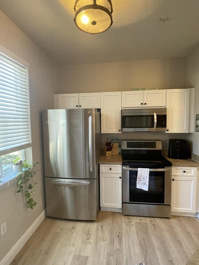 kitchen with white cabinets, light hardwood / wood-style floors, and appliances with stainless steel finishes