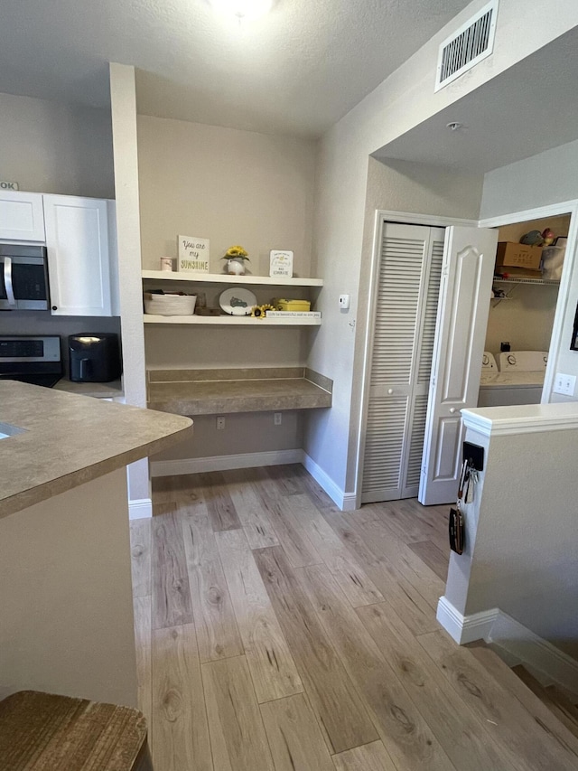 kitchen featuring white cabinetry, stove, and light wood-type flooring