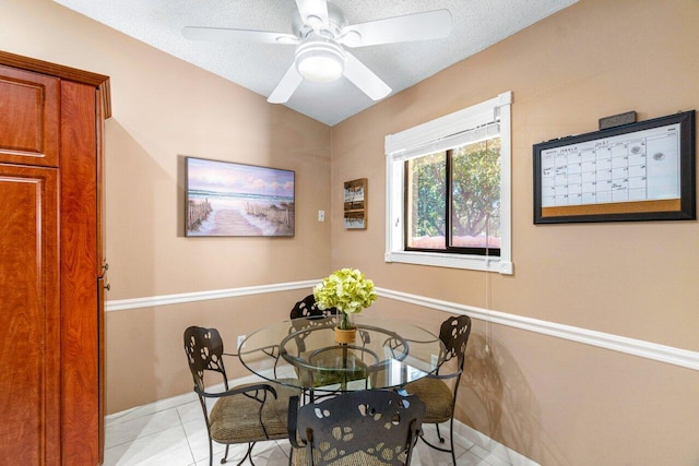 dining area with ceiling fan, light tile patterned floors, and a textured ceiling