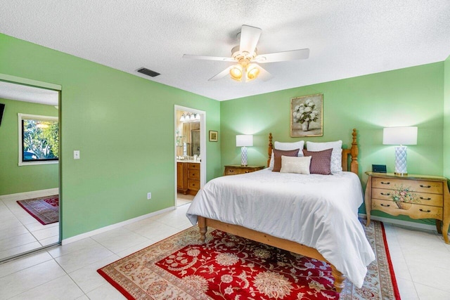 bedroom featuring light tile patterned floors, a textured ceiling, ensuite bathroom, and ceiling fan