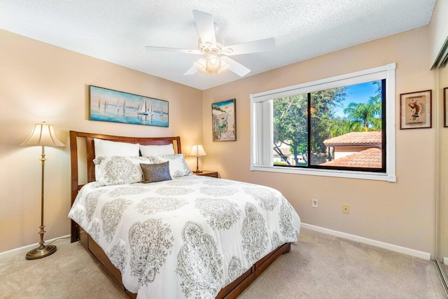 carpeted bedroom with ceiling fan and a textured ceiling