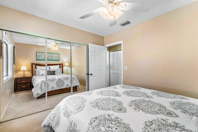 carpeted bedroom with a textured ceiling, a closet, and ceiling fan