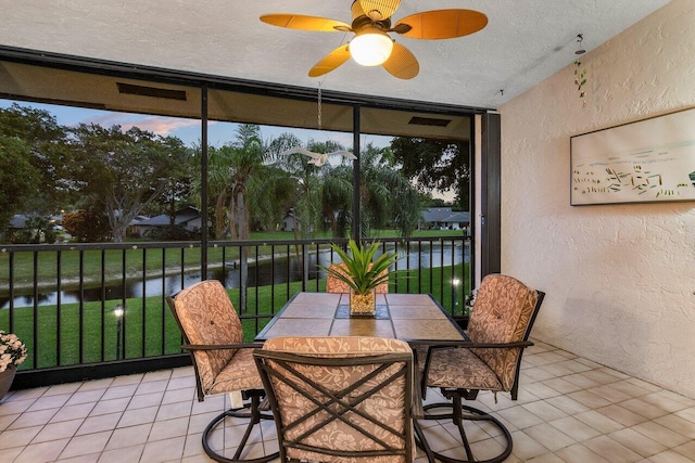 sunroom / solarium featuring ceiling fan and a water view