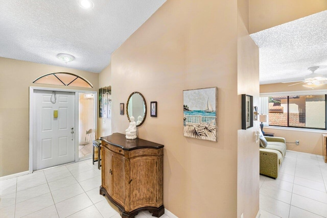 foyer featuring ceiling fan, light tile patterned flooring, and a textured ceiling