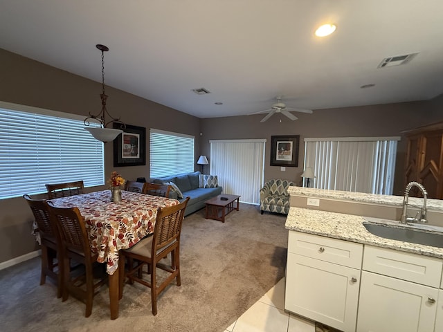 dining room with ceiling fan, light colored carpet, and sink