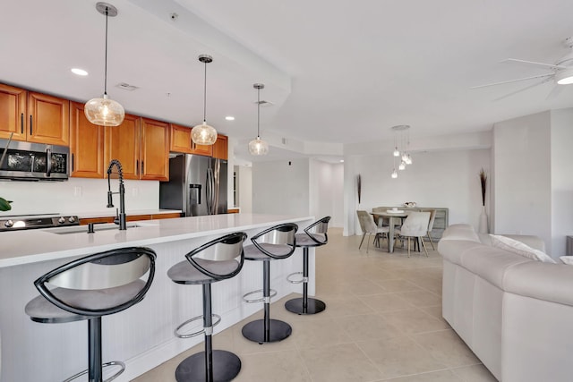 kitchen featuring ceiling fan, sink, decorative light fixtures, light tile patterned flooring, and appliances with stainless steel finishes