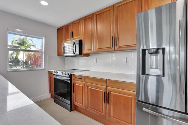 kitchen with decorative backsplash, light tile patterned flooring, light stone counters, and appliances with stainless steel finishes