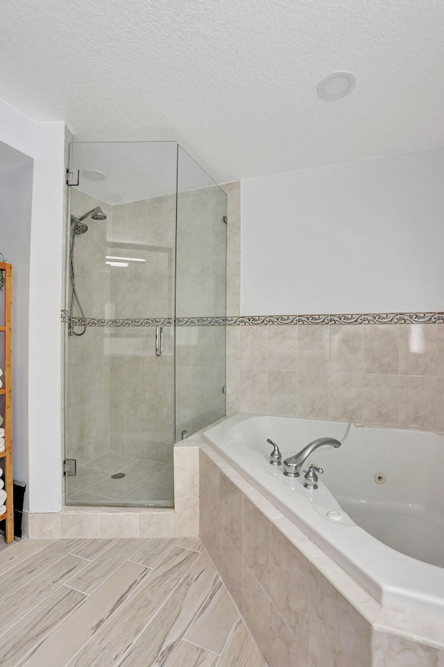 bathroom with a textured ceiling and independent shower and bath