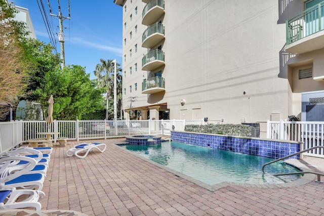 view of swimming pool featuring a community hot tub, pool water feature, and a patio