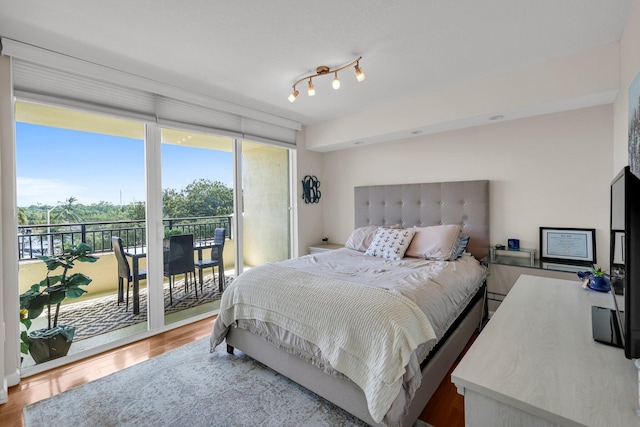 bedroom featuring access to outside, hardwood / wood-style floors, and a wall of windows