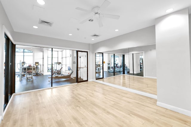 exercise room featuring ceiling fan, a healthy amount of sunlight, and light hardwood / wood-style floors