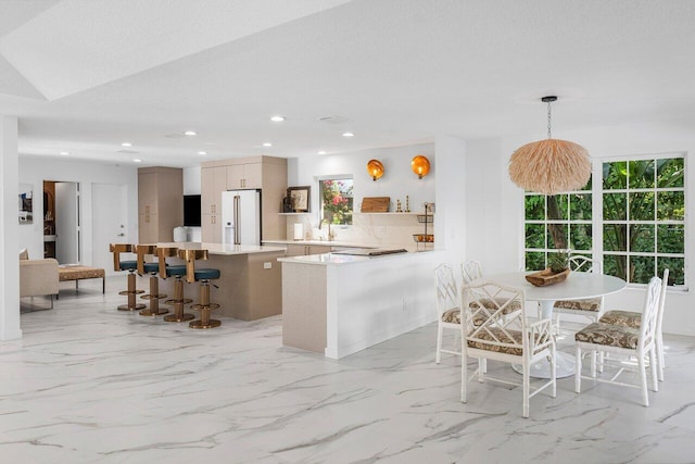 kitchen with a center island, sink, decorative light fixtures, kitchen peninsula, and high end white refrigerator