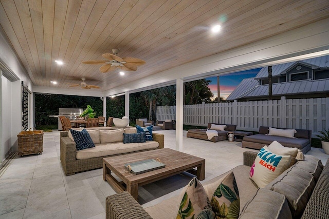 patio terrace at dusk with an outdoor living space, ceiling fan, and exterior kitchen